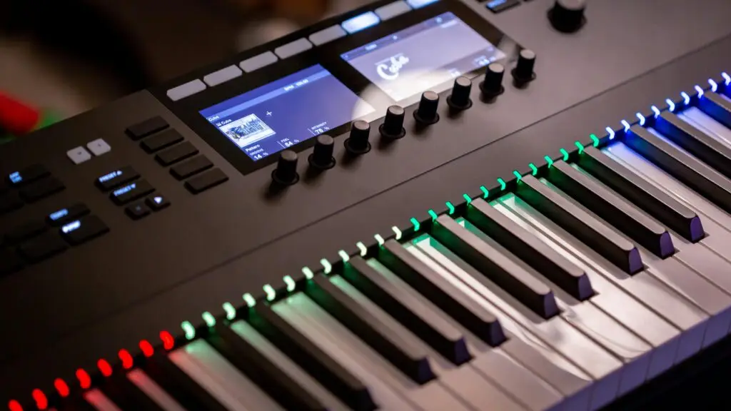 Close-up of an electronic Komplete Kontrol keyboard with colorful illuminated keys in a studio setting.